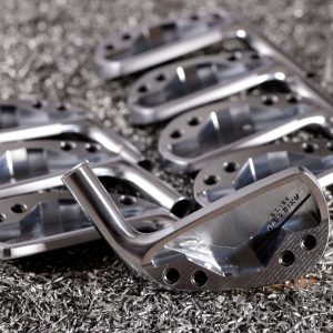 Forged AXIS Golf iron heads resting on milling swarf